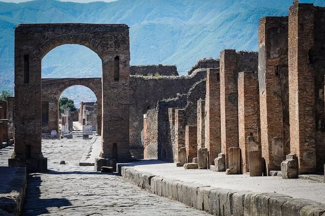 A Roman street in Pompeii with high kerbs, big paving stones and a brick arch